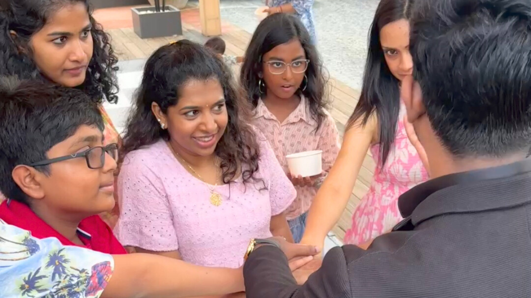 A professional wedding magician in Chennai performing an interactive magic trick for a bride and groom during their wedding reception. The magician, dressed in a stylish blazer, is astonishing the crowd with a blend of close-up illusions and mind-reading effects. The background features joyful wedding guests of all ages laughing and applauding. This vibrant and colorful image captures the essence of modern wedding entertainment in Chennai — fun, unforgettable, and unique.